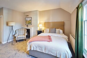 Une chambre d’hôtel avec un grand lit, une chaise, une table de chevet, une lampe et un tableau encadré au mur.