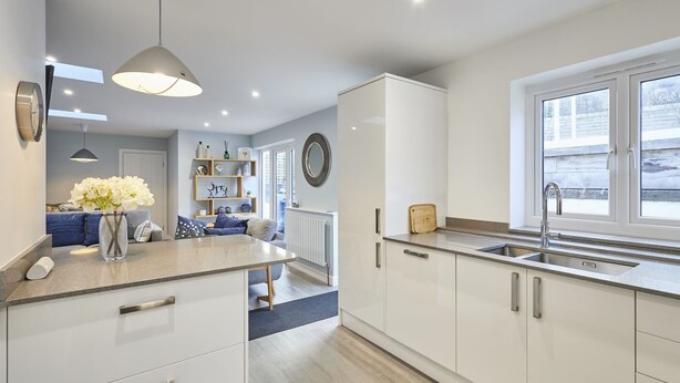 A modern kitchen with white cabinets, a central island, and a window with a view of the outside. - Host Stay Harrow Bothy (Berwick-upon-Tweed)