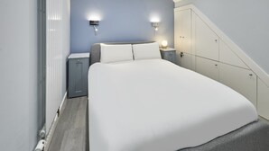 A bedroom with a large bed, two bedside tables, a wardrobe, and a sloped ceiling. - Host Stay Harrow Bothy (Berwick-upon-Tweed)