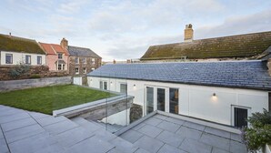 A modern house with a flat roof, a small garden, and a paved patio area. - Host Stay Harrow Bothy (Berwick-upon-Tweed)