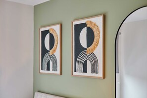 Twee ingekaderde abstracte kunstwerken aan een lichtgroene muur.
