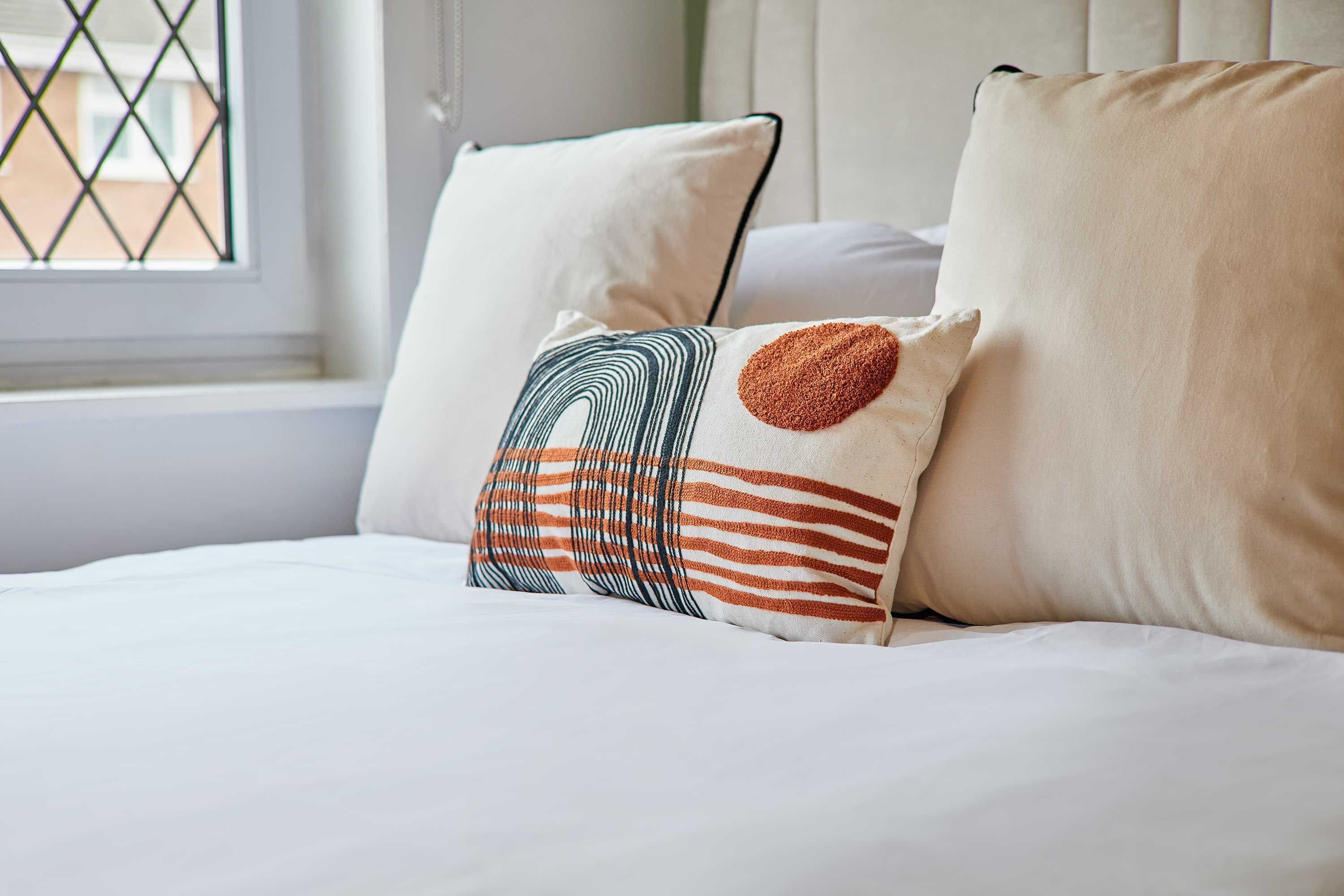 A bed with white bedding and decorative pillows.
