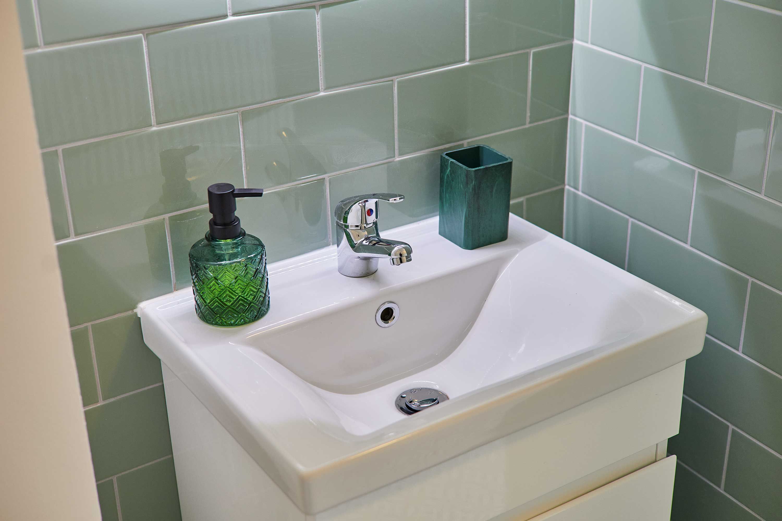 A bathroom sink with a soap dispenser and a faucet.