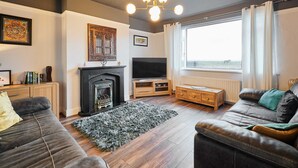 A living room with a fireplace, a television, and a large window with curtains.