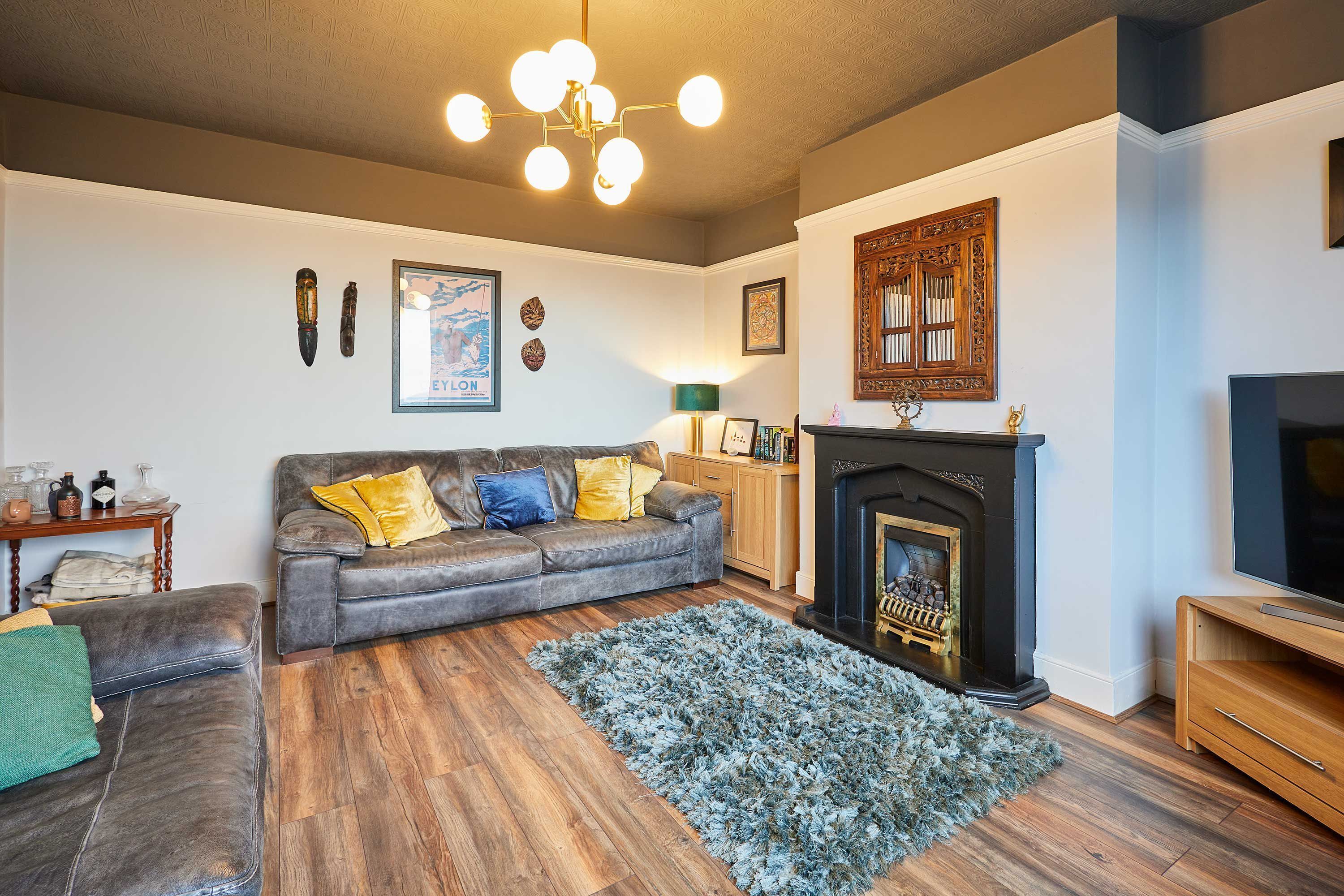 A living room with a fireplace, a sofa, a television, and a wooden floor.