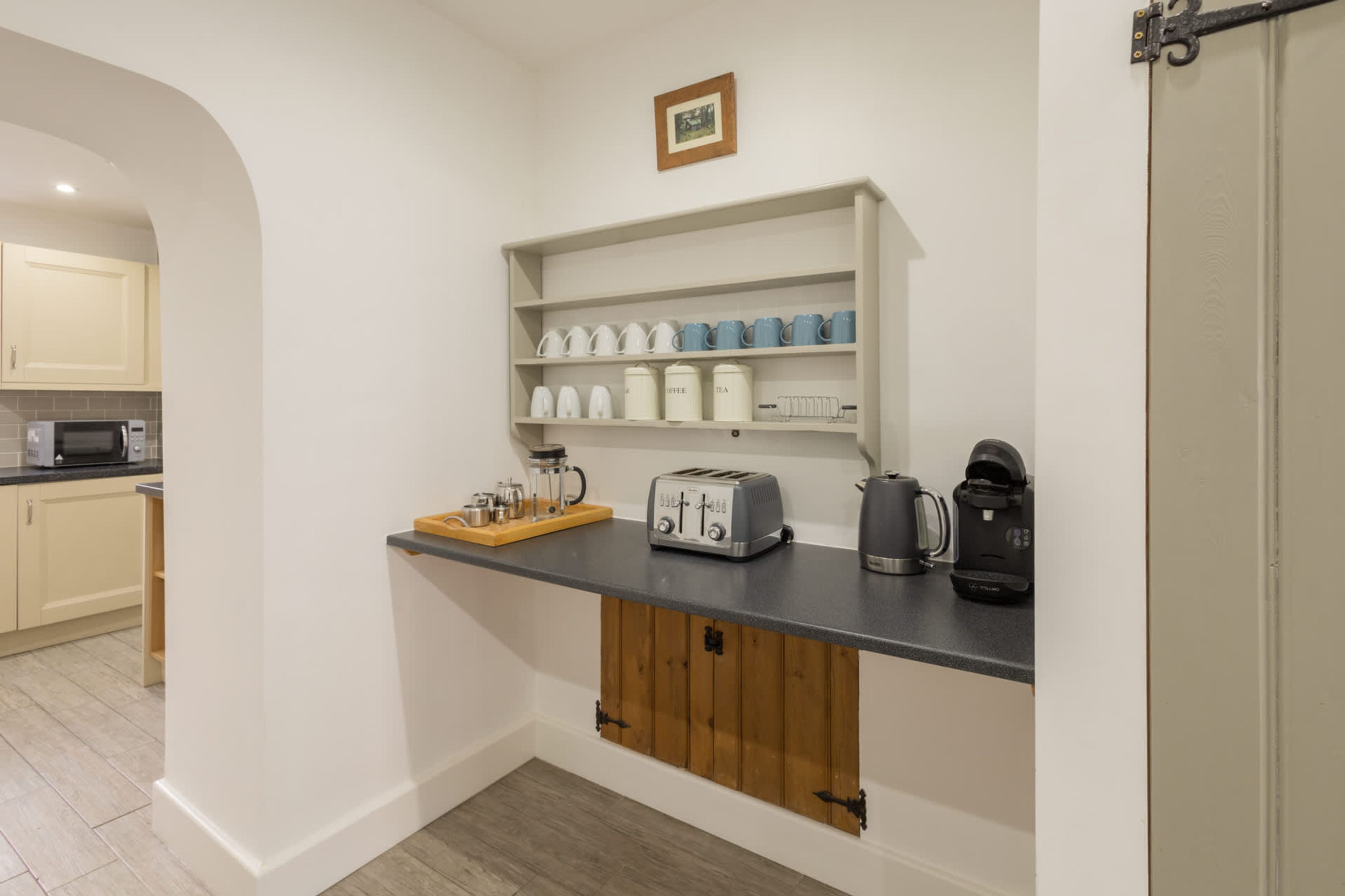 A kitchen with white cabinets, a microwave, a toaster, and a coffee maker on the counter.