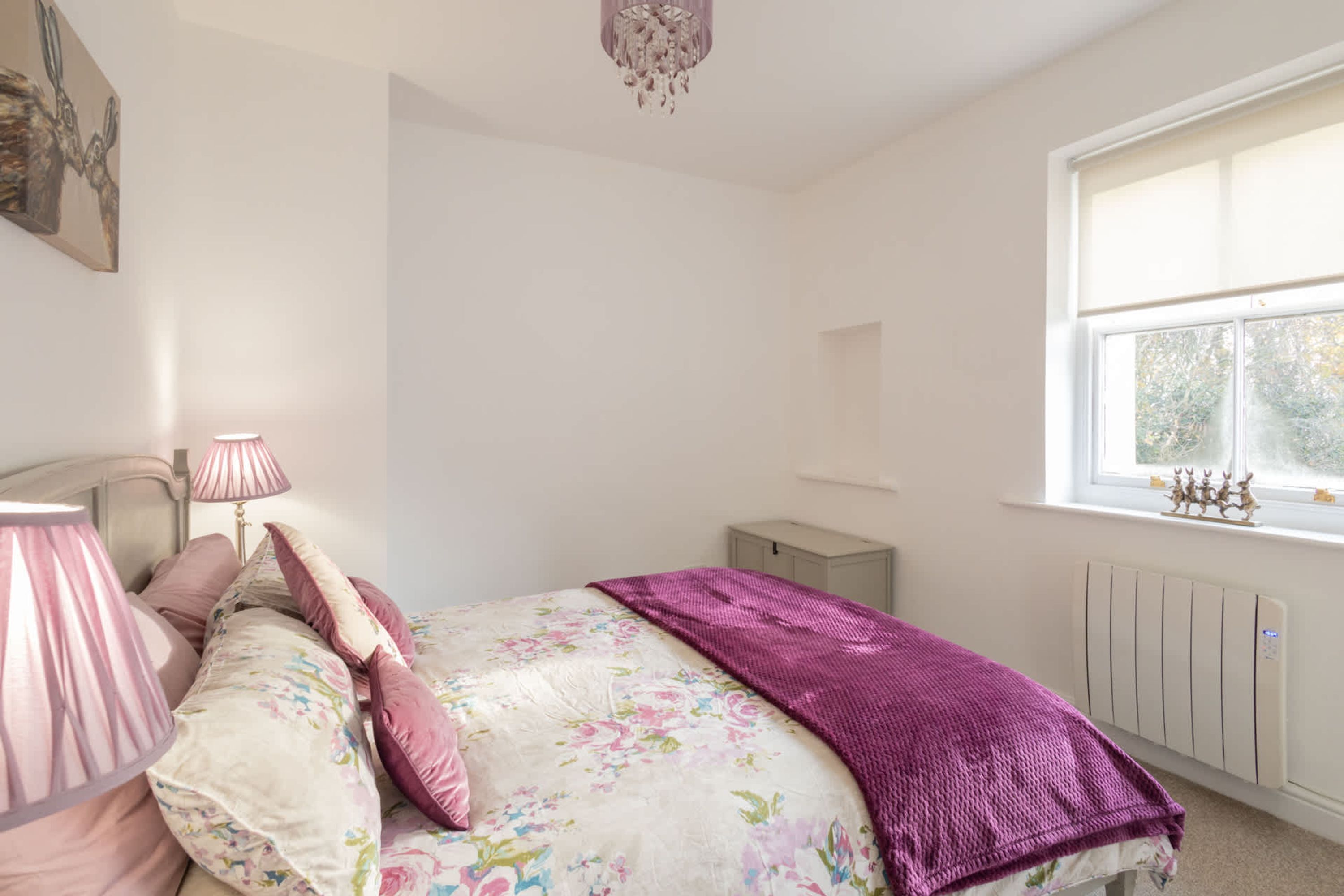 Een slaapkamer met een bed, twee bedlampen, een raam en een radiator.
