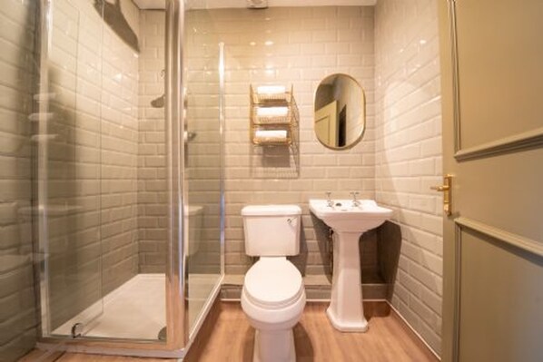 A bathroom with a glass shower enclosure, a toilet, and a pedestal sink.