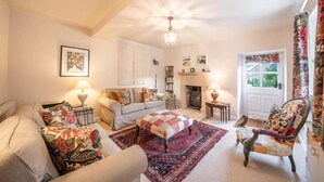 A cozy living room with a sofa, armchair, ottoman, fireplace, and a ceiling fan. - Host Stay White House (Matlock)