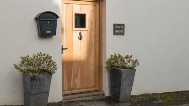A wooden door with a mailbox and a sign reading "WHITE HOUSE" on a white wall. - Host Stay White House (Matlock)