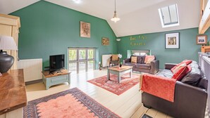 A living room with a high ceiling, green walls, a fireplace, a television, a sofa, and a coffee table. - Host Stay Nine Ladies (Matlock)