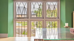 A room with a large window featuring a white frame and diamond-patterned glass. - Host Stay Nine Ladies (Matlock)