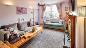 Een gezellige woonkamer met een grijze bank, een blauwgroene bank en een houten salontafel.