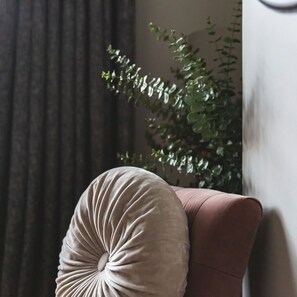 A room with a dark curtain, a plant, and a cushion on a pink sofa. - Host Stay 44 Wellington Street (Matlock)