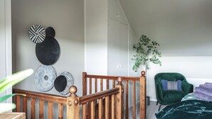 A room with a wooden staircase, a green armchair, and a radiator. - Host Stay 44 Wellington Street (Matlock)