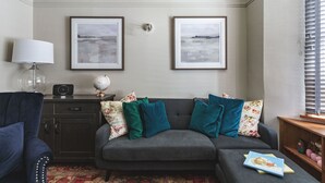 A living room with a grey sofa, two framed pictures on the wall, a globe, a lamp, and a bookshelf. - Host Stay 44 Wellington Street (Matlock)