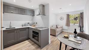 A modern kitchen with grey cabinets, a built-in oven, and a central island. - Host Stay Rock Mill 37 Cavendish (Hope Valley)