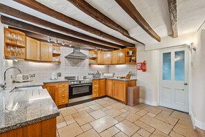 Kitchen features a stainless steel sink, double oven, and range hood, with a microwave and coffee maker.