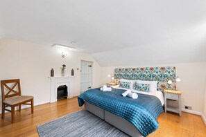 Cozy bedroom with a large bed, wooden chair, and fireplace.