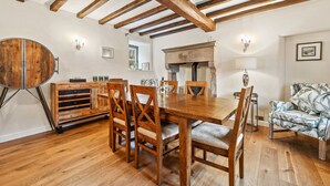 A dining area with a wooden table and chairs, a round wooden cabinet, and a fireplace.