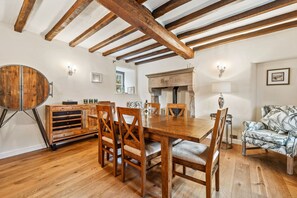 Cozy dining area with a wooden table and chairs, exposed beams, and a fireplace.