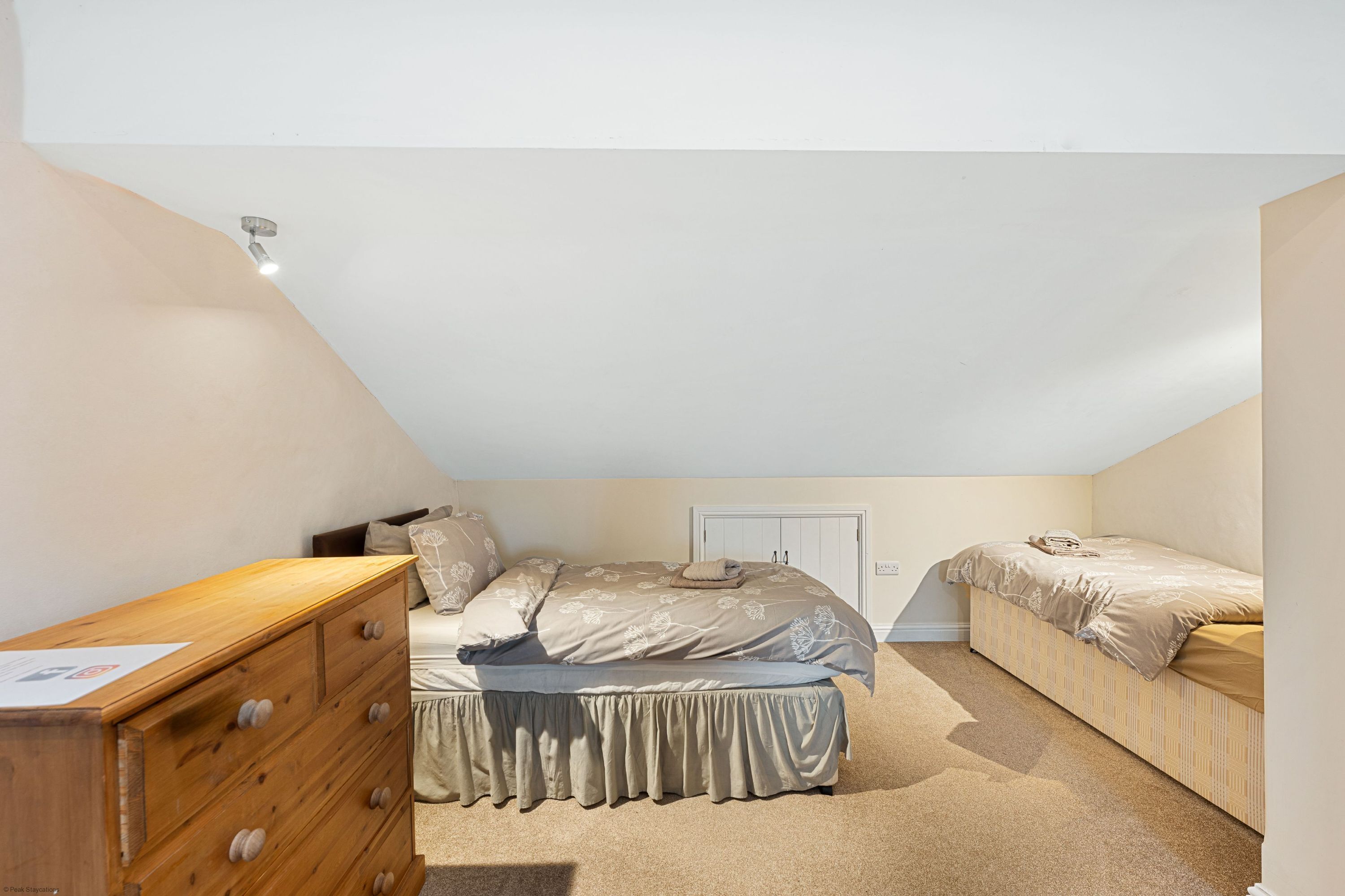 Een slaapkamer met een enkel bed, een houten dressoir en een kast.
