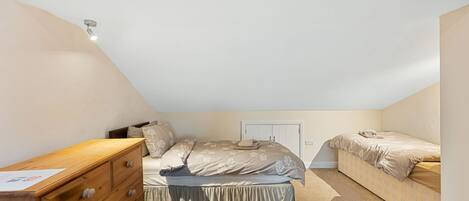 Een slaapkamer met een enkel bed, een houten dressoir en een kast.