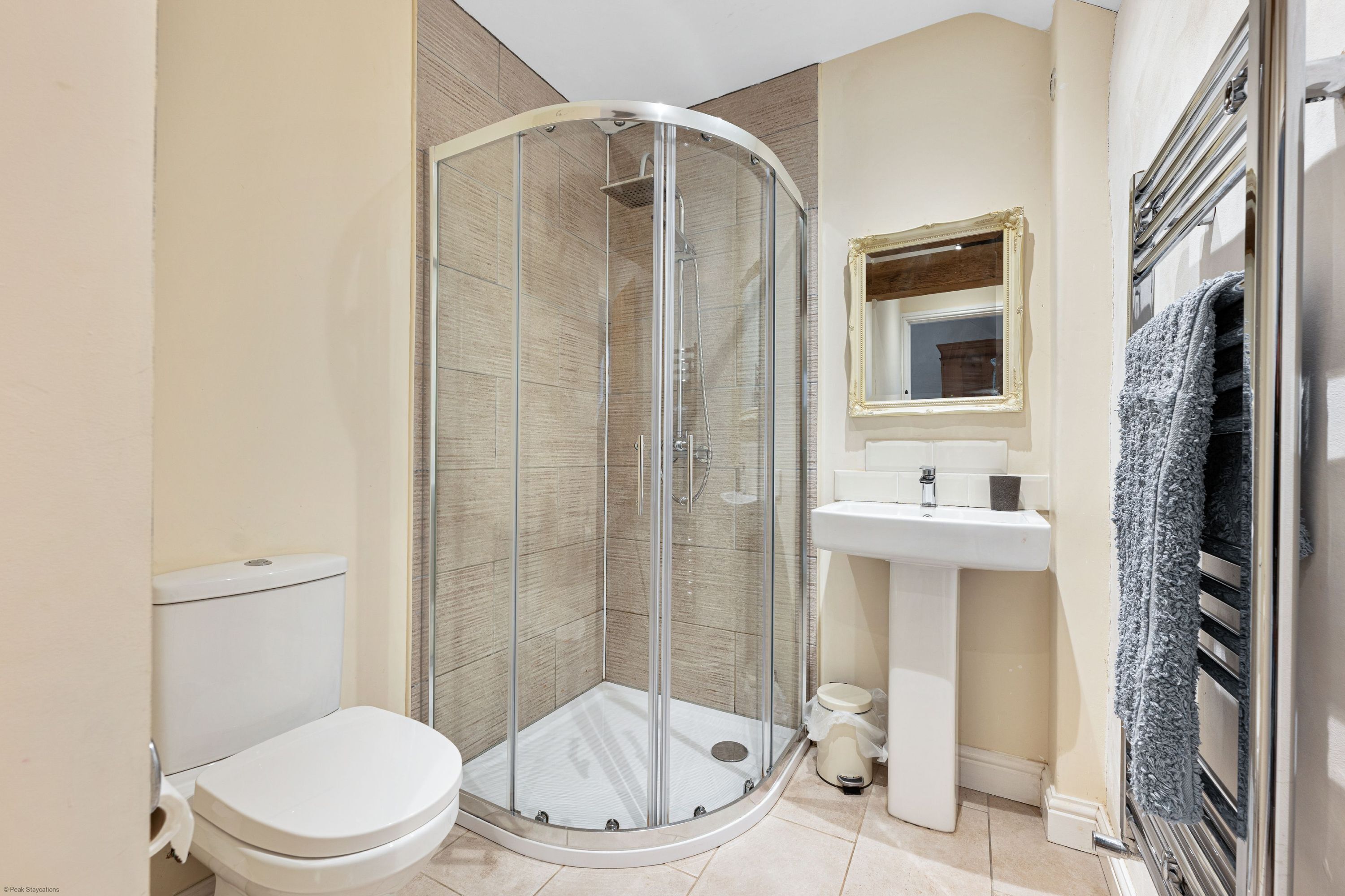 A bathroom with a glass-enclosed shower, a toilet, a sink, and a towel rack.