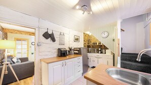 Eine kleine Küche mit weißen Schränken, einer Holz Arbeitsplatte und einem Edelstahl-Spülbecken.