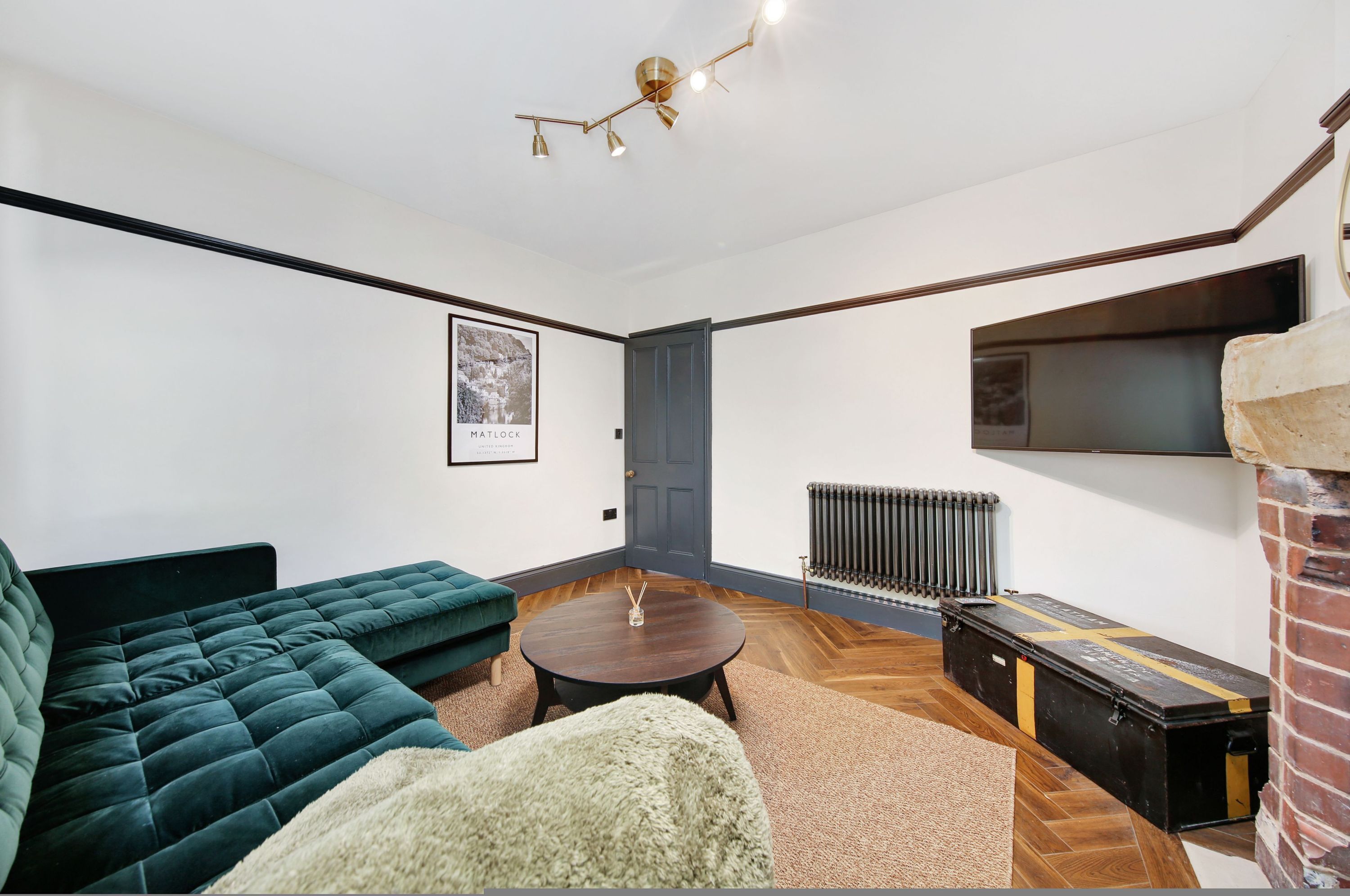 A modern living room with a green sofa, a round coffee table, and a fireplace.
