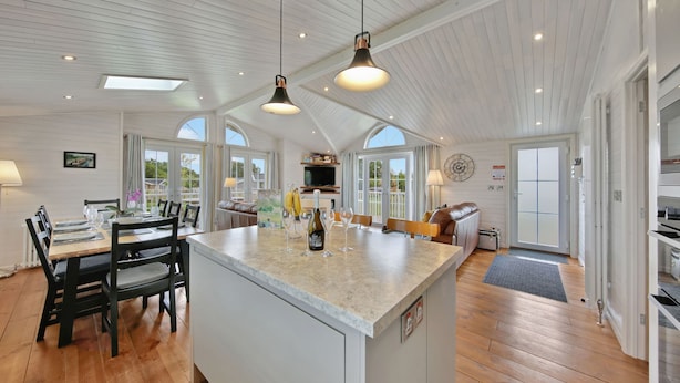 Una cocina amplia con una isla grande, piso de madera e iluminación colgante.