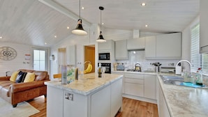 Una cocina moderna con armarios blancos, una isla central e iluminación colgante.