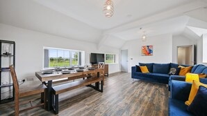 Ein großzügiger Wohnbereich mit Esstisch, blauem Sofa und Holzboden.