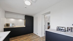 Eine moderne Küche mit Holzboden, weißen Arbeitsplatten und dunklen Schränken.