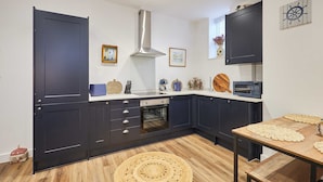 A modern kitchen with dark cabinets, a stainless steel range hood, and a wooden floor. - Host Stay The Coach House Apartment 2 (Saltburn-by-the-Sea)