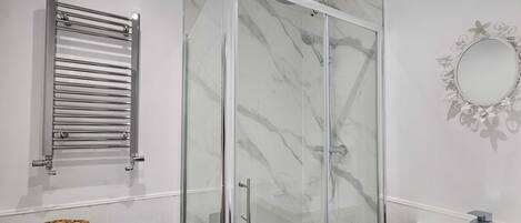 Un baño moderno con ducha de vidrio, lavabo blanco y un perchero para toallas.