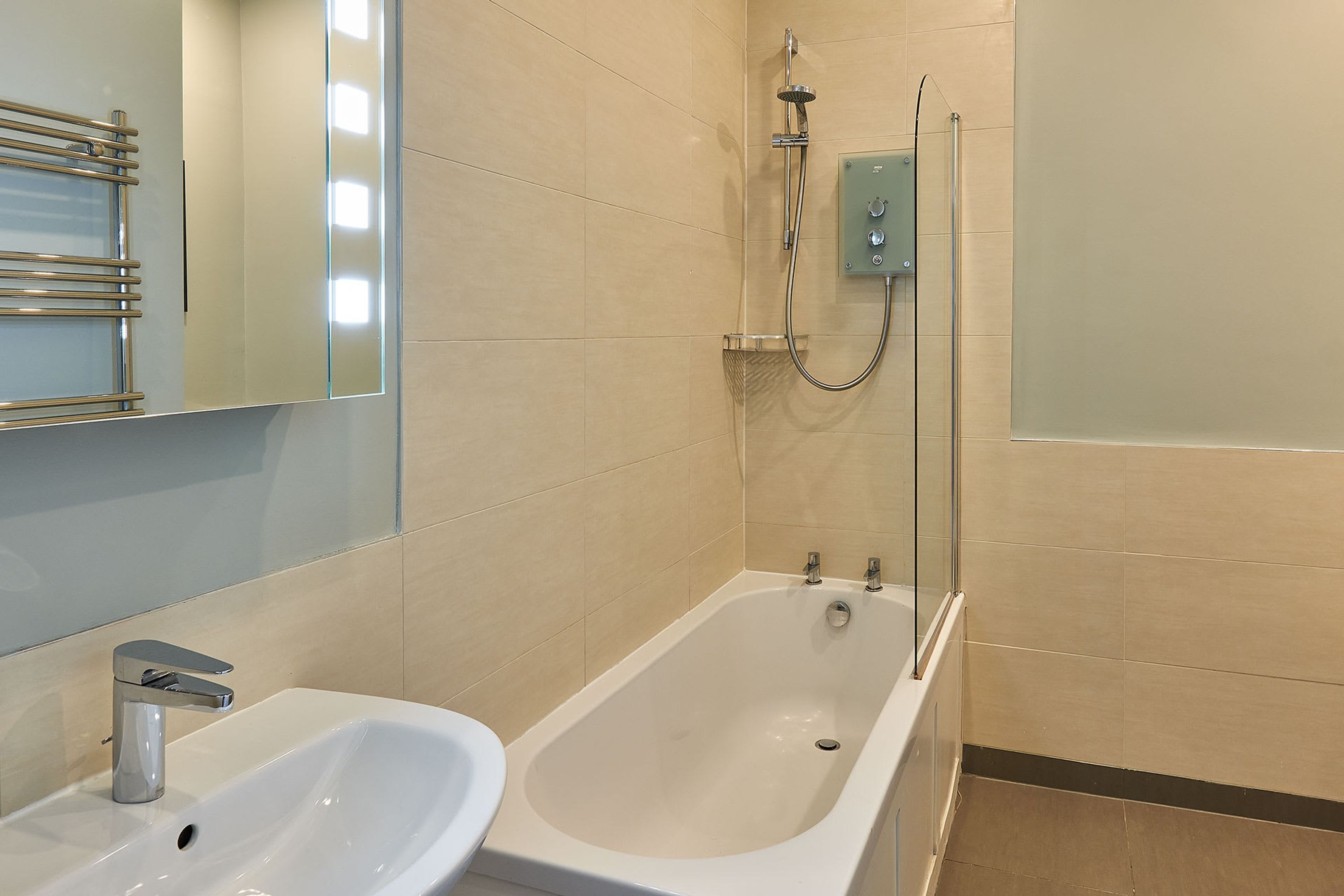 A modern bathroom with a white sink, a bathtub, and a glass-enclosed shower.