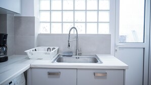 A modern kitchen with a stainless steel sink, a coffee maker, and a basket on the countertop.