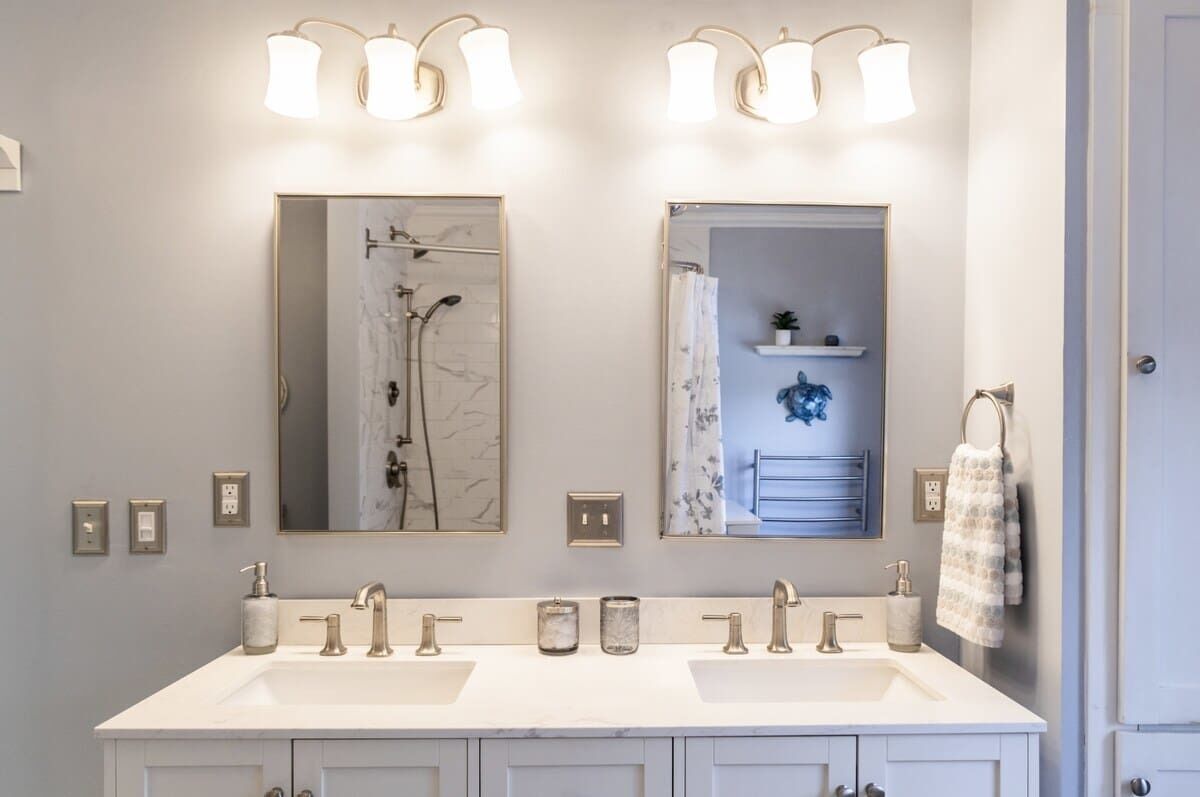 A bathroom with two sinks, a shower, and a mirror.