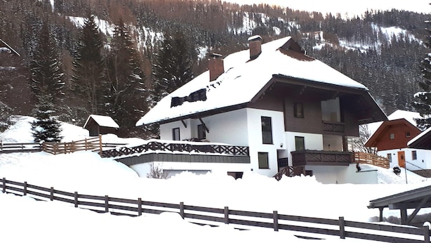 A snow-covered house with a wooden fence in the foreground. - Apartment in Bad Kleinkirchheim Near Hiking (Bad Kleinkirchheim)