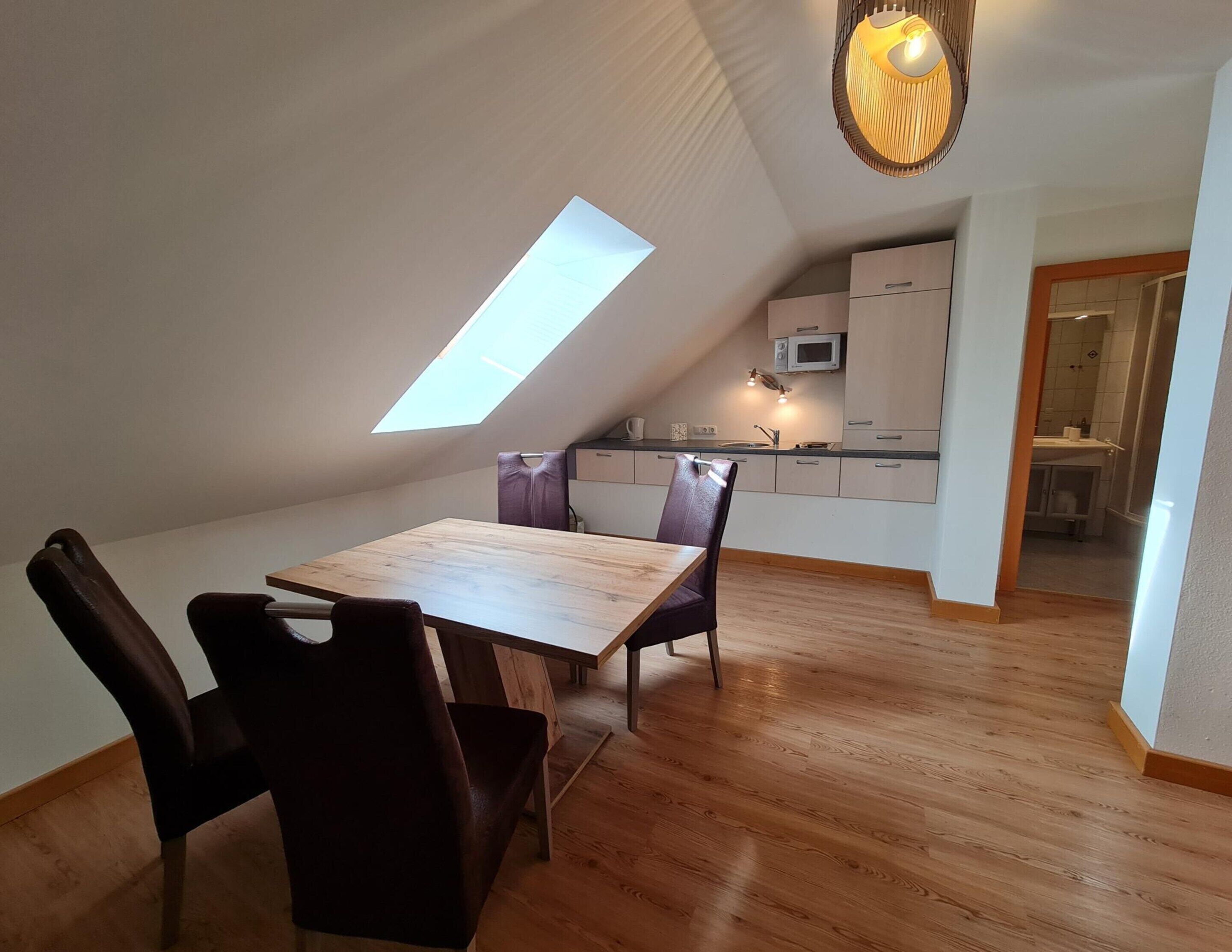 Una cocina moderna con tragaluz, suelo de madera y un comedor con mesa y sillas.