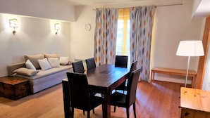 Ein Essbereich mit Holztisch und Stühlen, einer Couch mit Kissen, einer Bank und einer Lampe.
