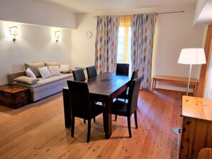 En matplats med ett träbord och stolar, en soffa med kuddar, en bänk och en lampa.