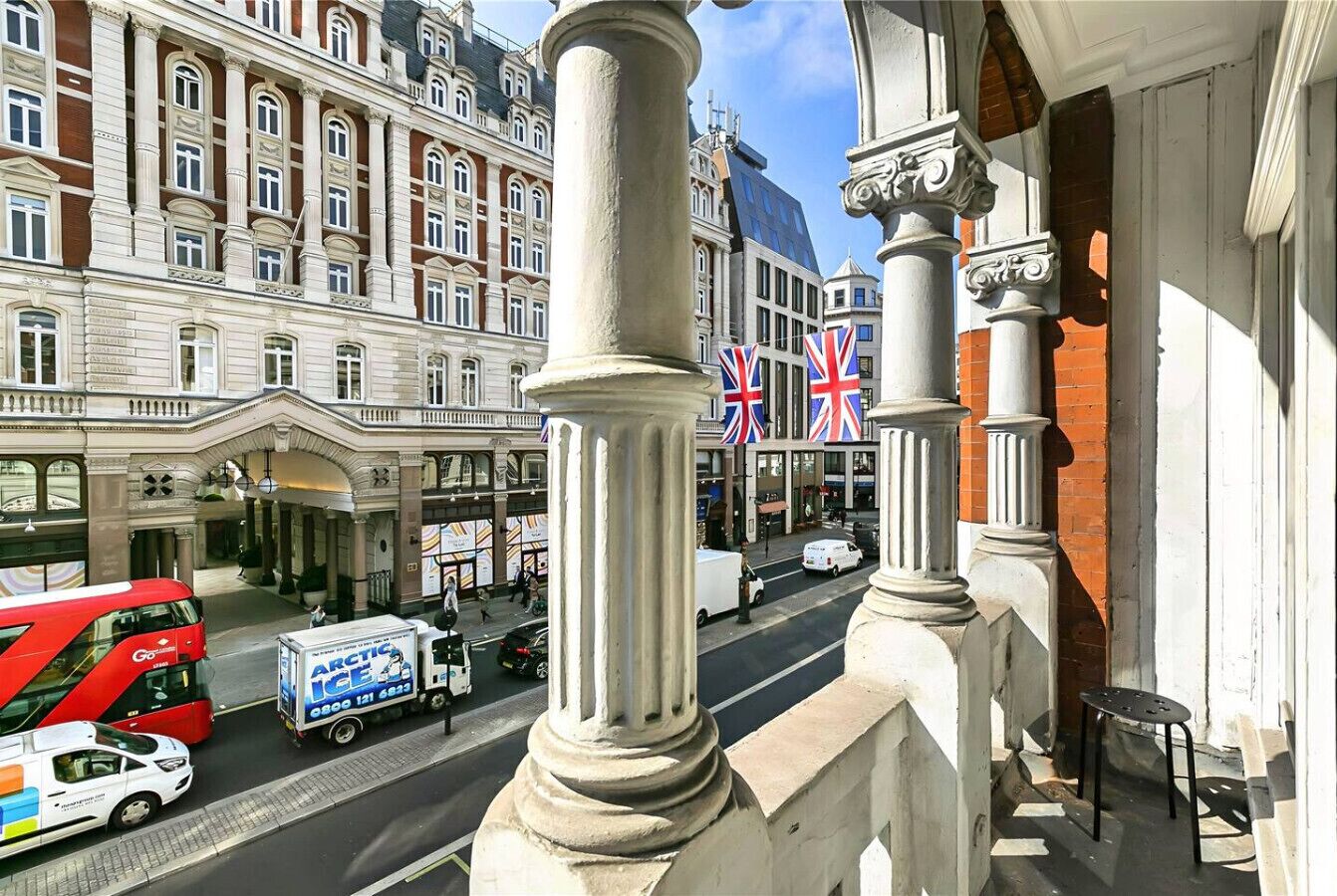 Vista de una calle con un edificio de arquitectura clásica, que incluye columnas y un balcón.