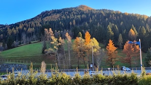 Un parcheggio con auto, un muro in pietra e una montagna sullo sfondo.