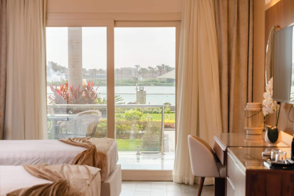 A modern hotel room with a large bed, a desk, and a view of the outdoors.
