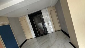 Un pasillo amplio con suelo de baldosas y una puerta que da a una habitación.