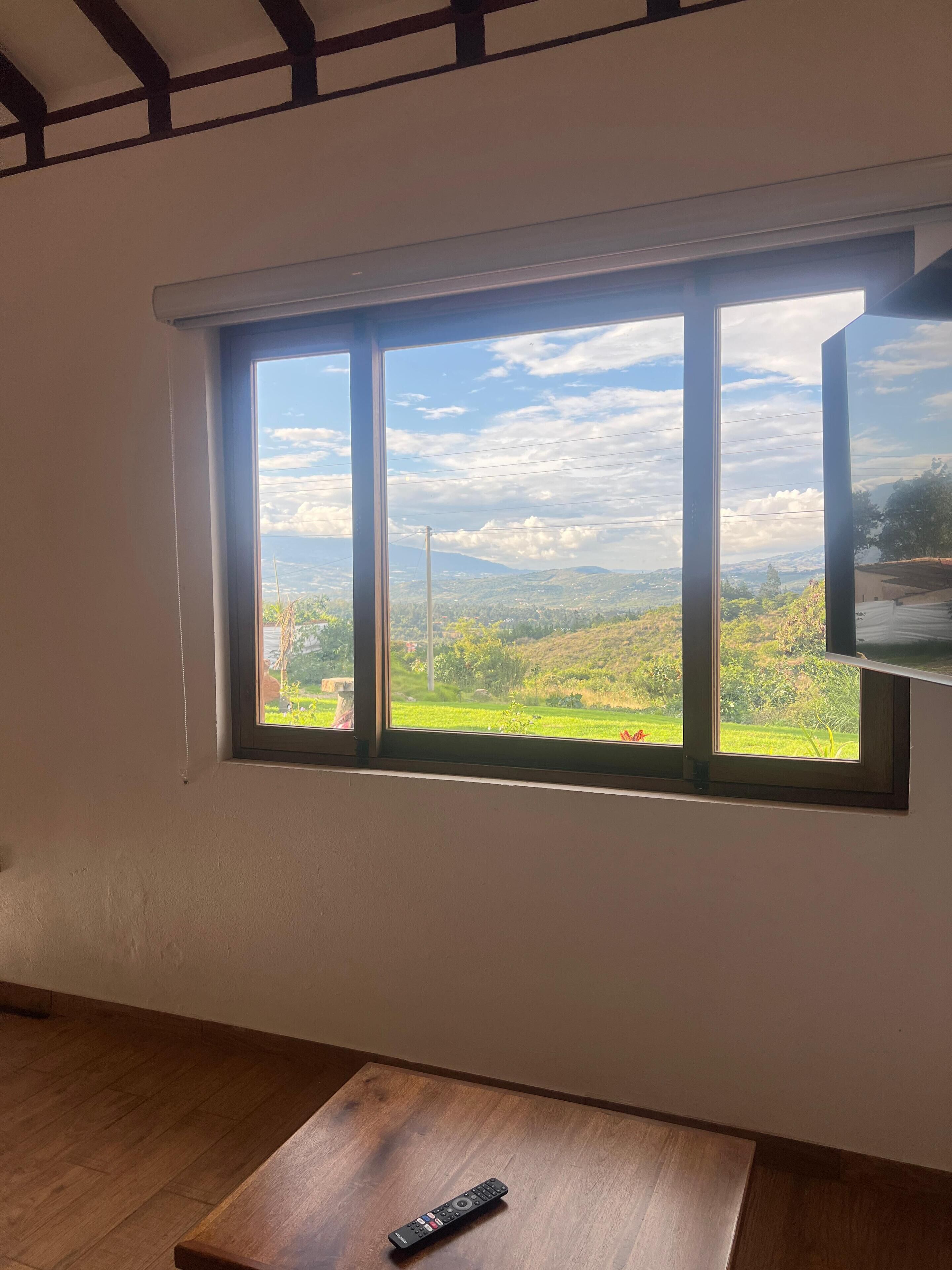 A room with a large window offering a view of a green landscape and distant hills.