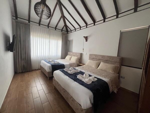 Une chambre d’hôtel avec deux lits, un plancher en bois, une grande fenêtre avec des rideaux, un luminaire au plafond et un téléviseur à écran plat.
