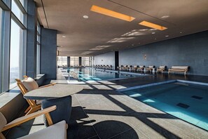 Una piscina interior moderna con sillones de descanso y zona de estar.